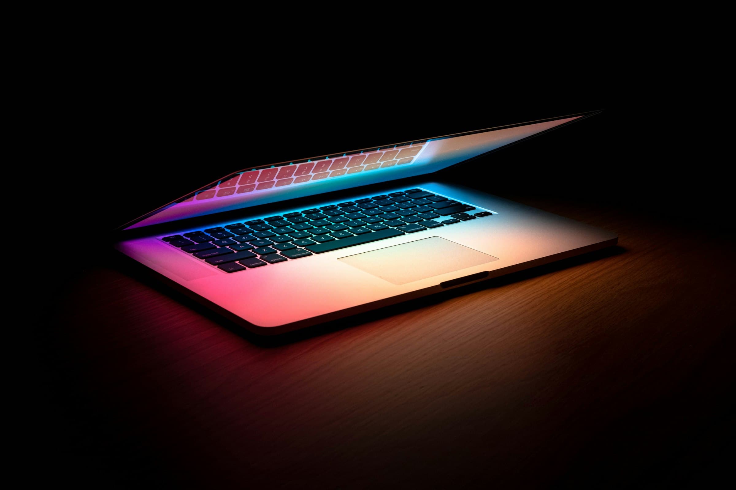 A laptop glowing with light in a dark, modern workspace