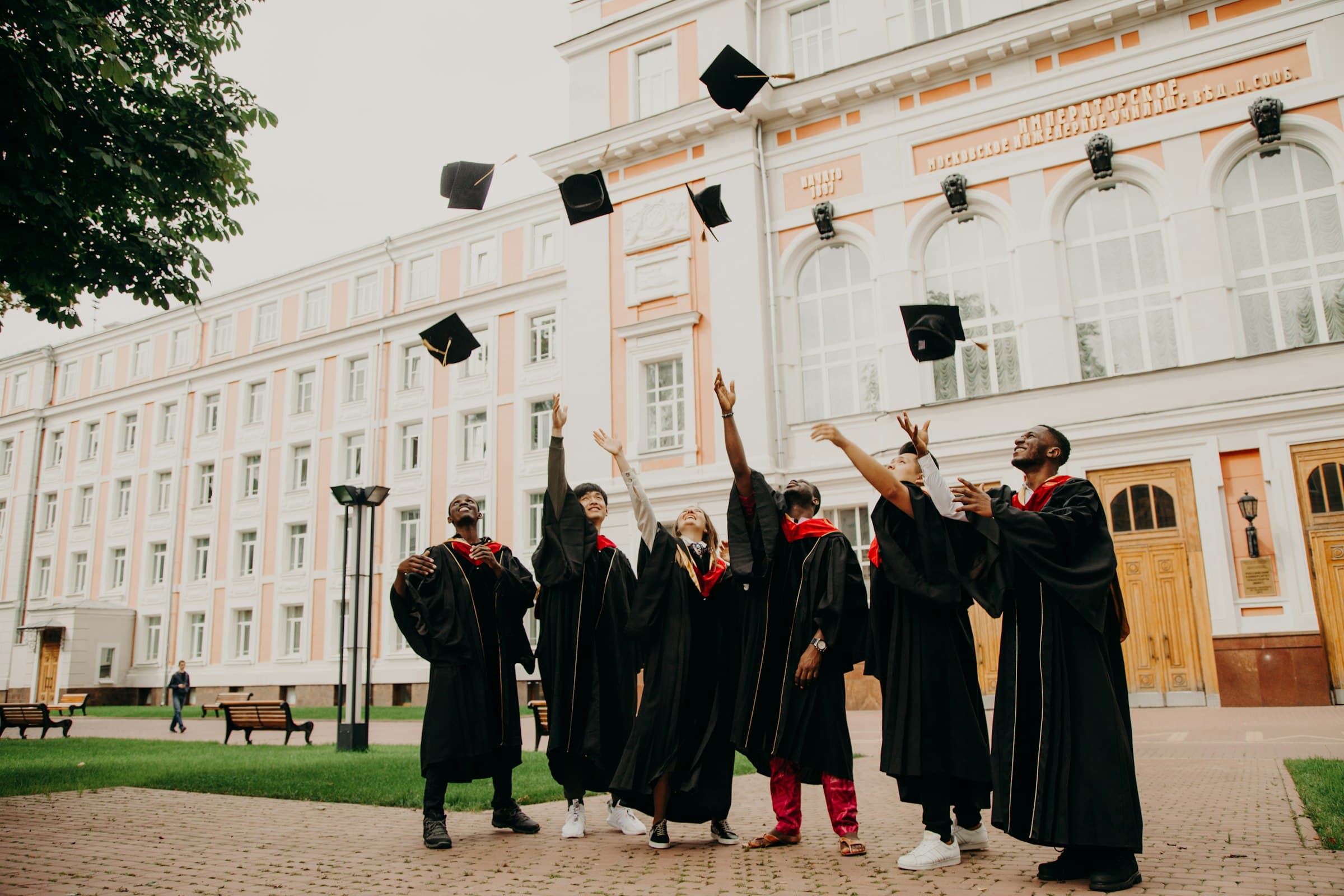Graduates celebrating, throwing their caps into the air outside their academic building
